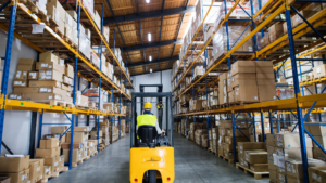 An employee driving a forklift in a warehouse.