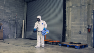 Person in a hazmat suit spraying a warehouse.