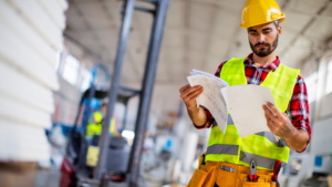 Employee reviewing plans in a warehouse.